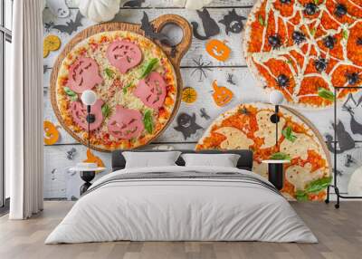 Halloween funVarious Halloween funny pizza. Halloween party recipe, Creative idea for Halloween pizza`s with ham and cheese ghosts, monster, spiders, white wooden background with Halloween decny pizza Wall mural